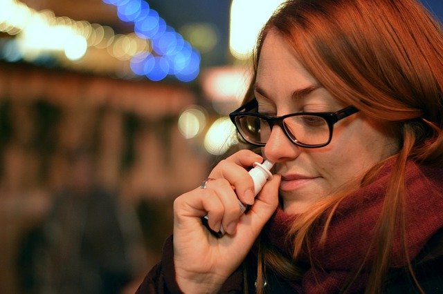 žena si stříká kapky do nosu